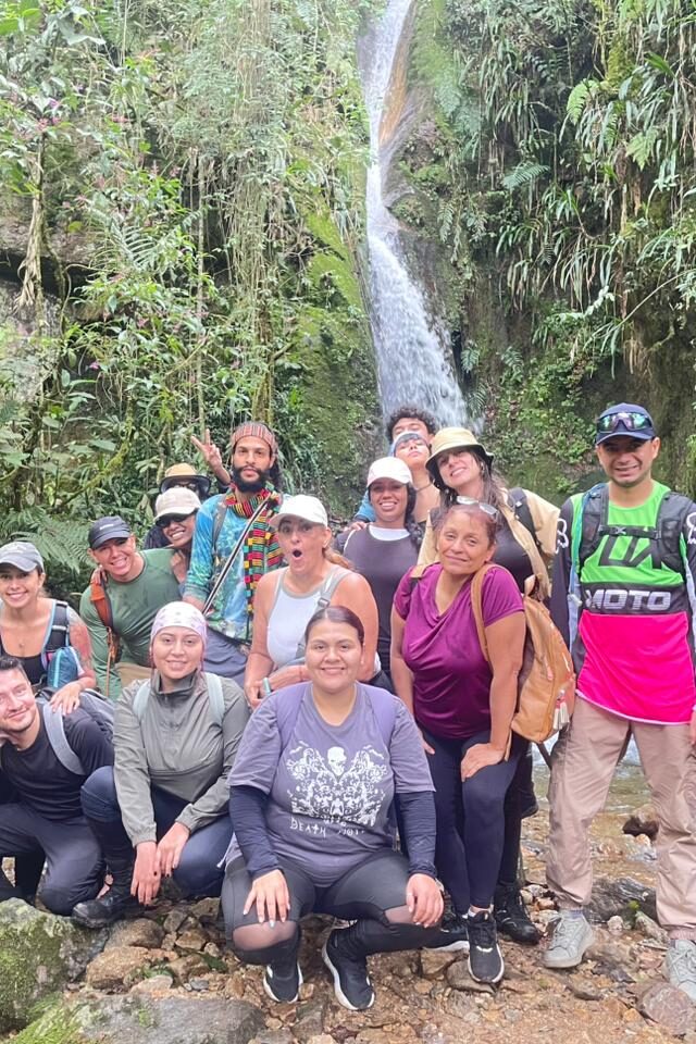 Foto grupal de senderistas frente a una cascada.